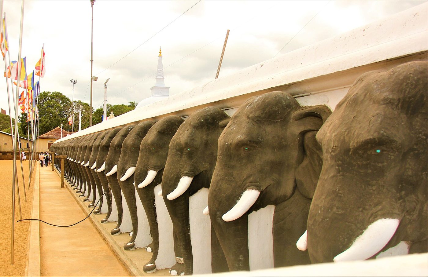 A row of carved elephant heads with white tusks along the wall of Ruwanwelisaya